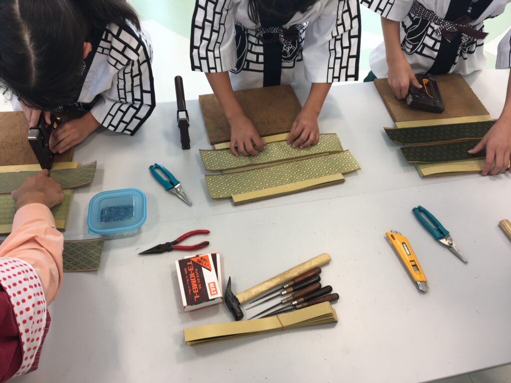 ミニ畳製作体験で畳表と畳縁を合わせて作業する様子
