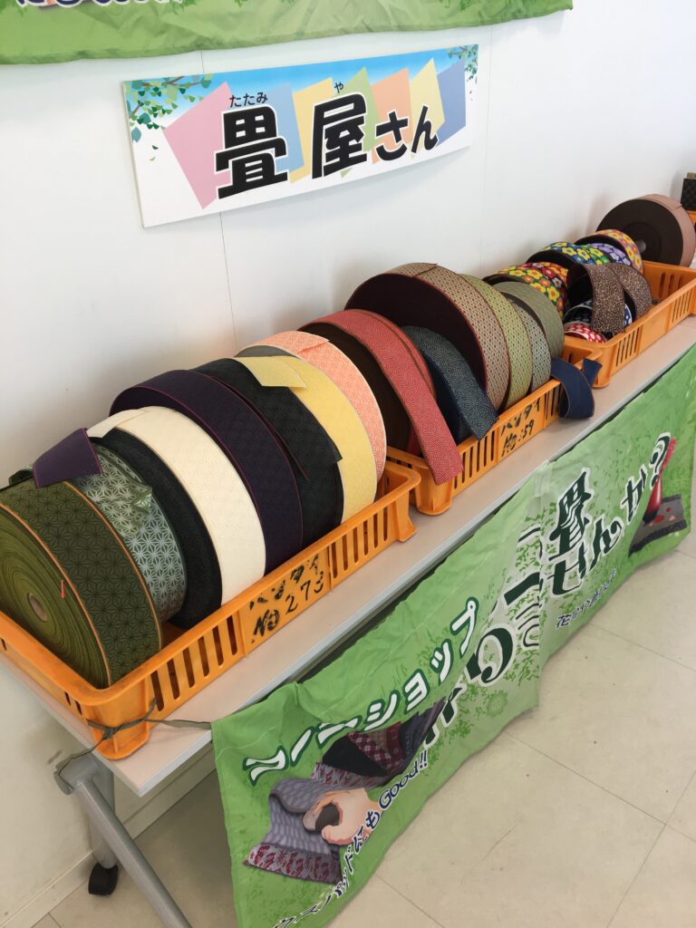 ミニ畳制作体験の出店ブースに並ぶ畳縁の見本と案内看板